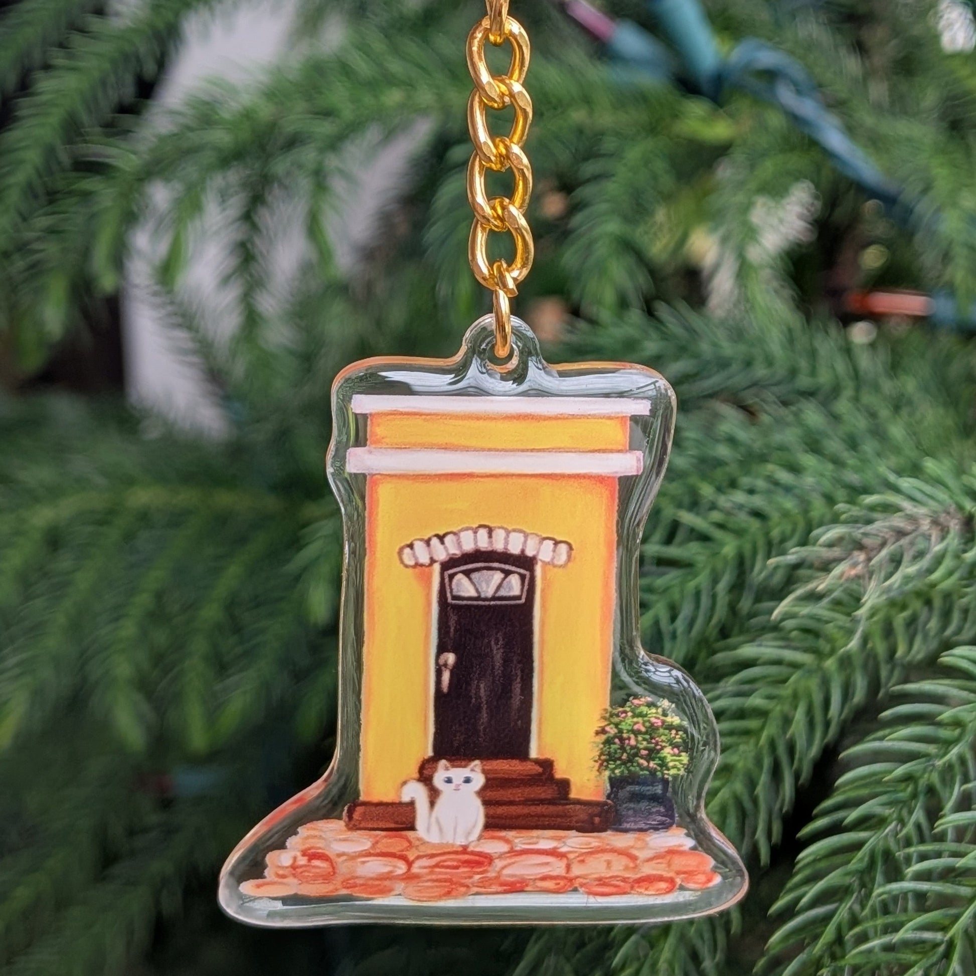 Keychain with a design of an Old San Juan house and white cat on a leafy background.