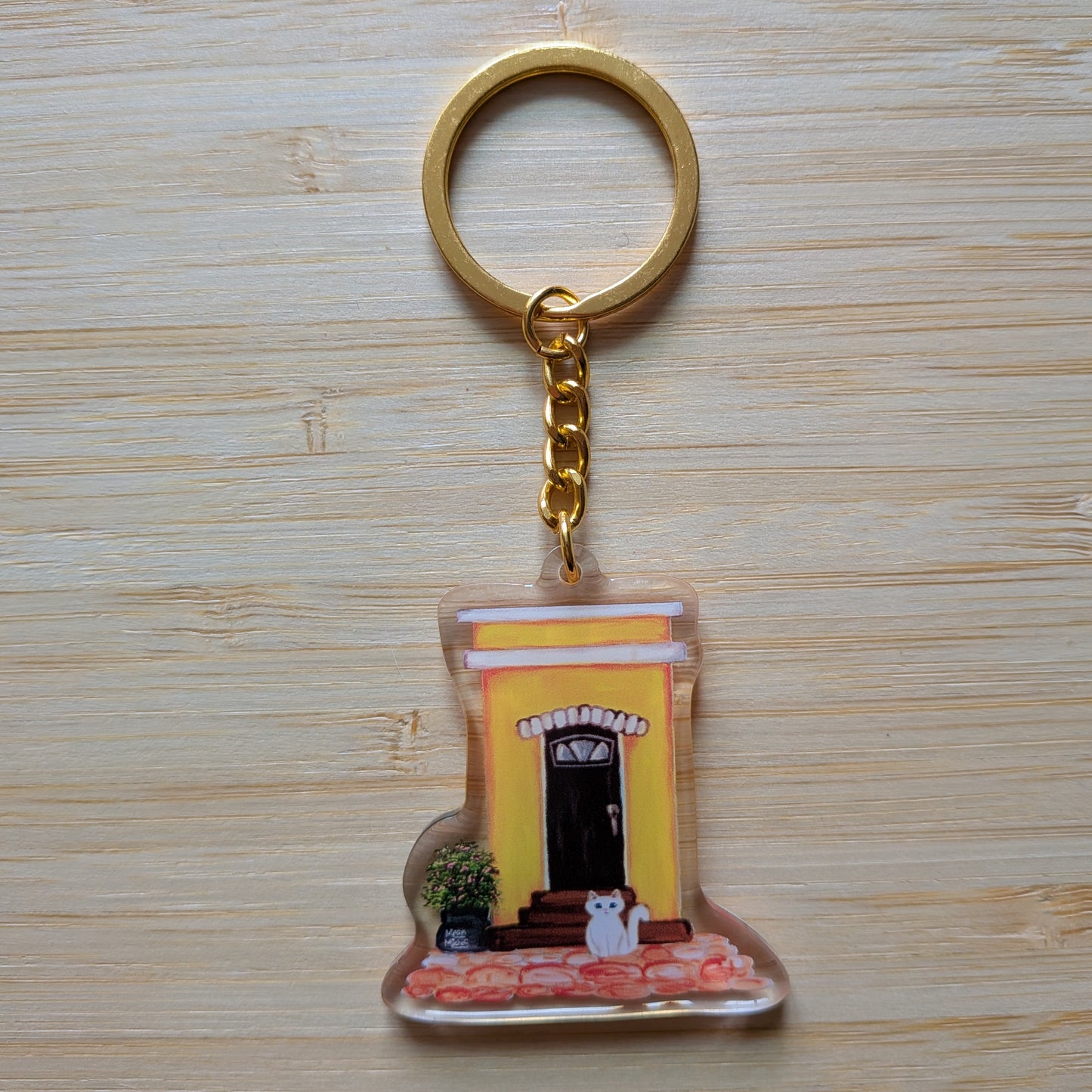 Keychain with a design of an Old San Juan house and white cat on a wooden surface